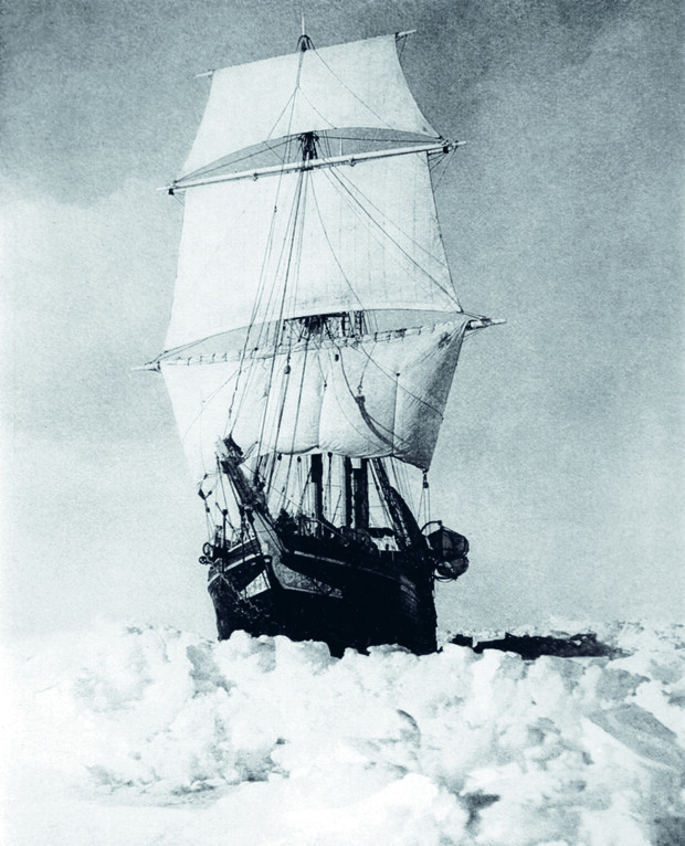 A large sailing ship with tall masts and sails is trapped in thick, rugged ice, with a bleak, cloudy sky above, creating an atmosphere of isolation and challenge.